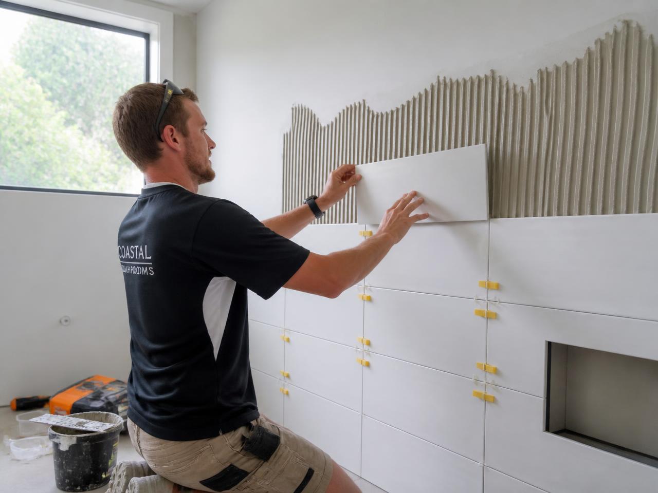 Tradesperson tiling a wall during a bathroom renovation
